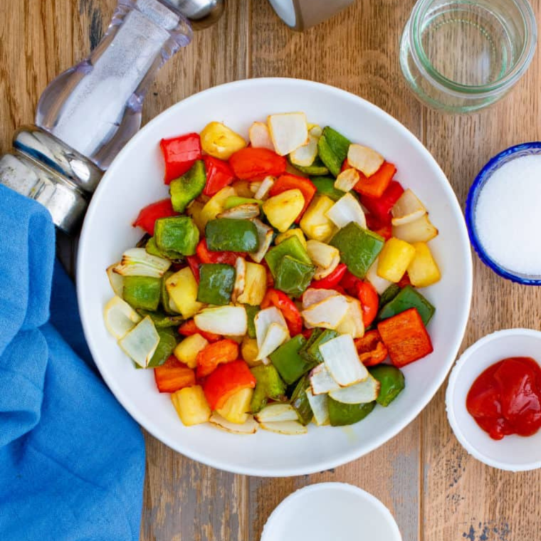 Chop bell peppers, broccoli, and carrots into uniform bite-sized pieces for even cooking while the pork marinates.