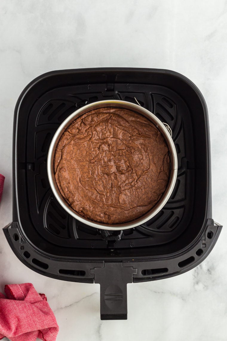 Brownie batter spread evenly in a six-inch springform pan, ready for the air fryer
