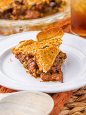 Air fryer beef pot pie in a white ramekin with a golden flaky crust cut open to show tender beef, carrots, and peas in brown gravy