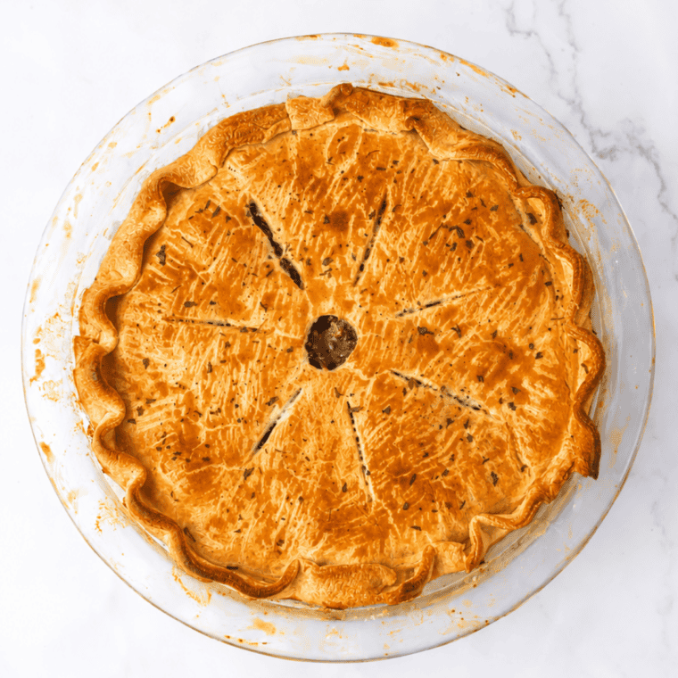 Finished pot pies with deep golden crusts and gravy bubbling up through the vent slits