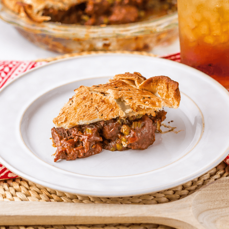 Spoon lifting a bite of air fryer beef pot pie with shredded beef, peas, and brown gravy under a flaky crust