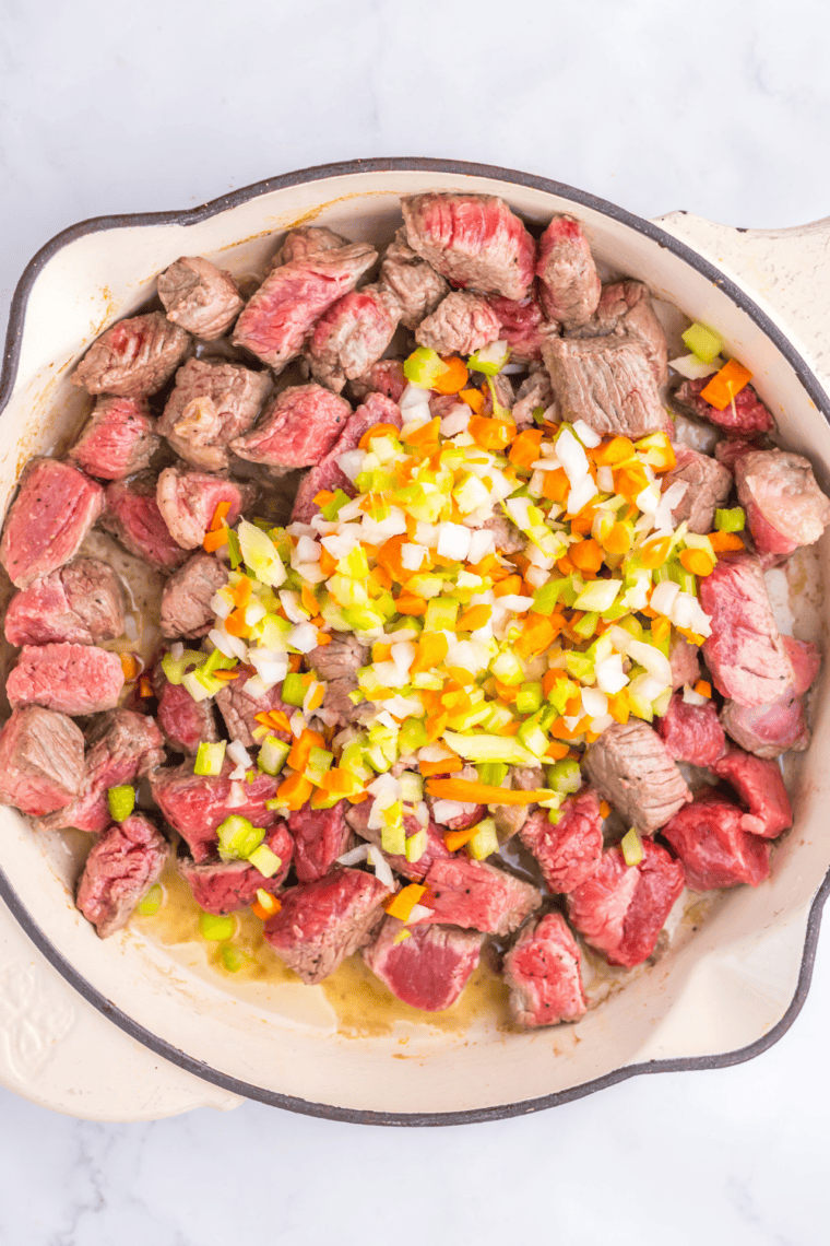 Cubes of beef stew meat searing in a single layer in a Dutch oven with dark brown crust forming