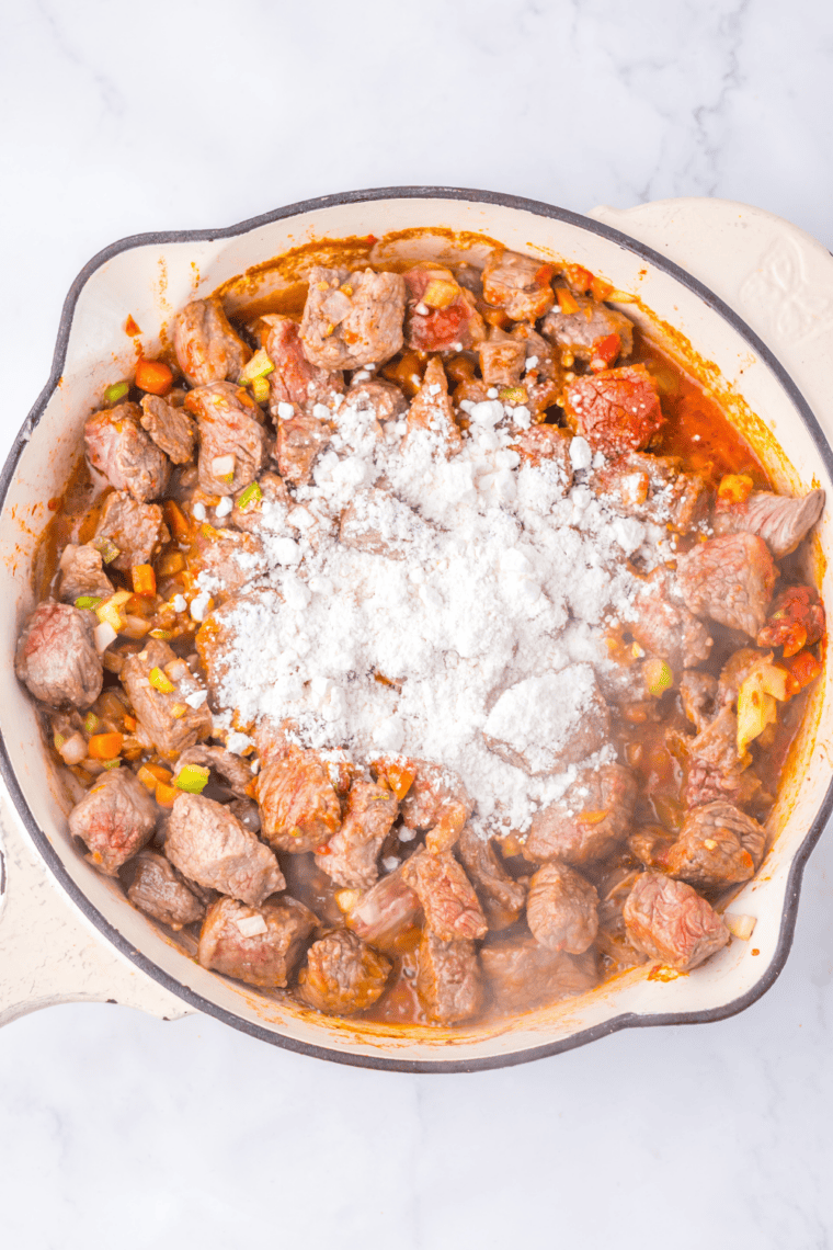 Flour stirred into vegetables in a Dutch oven forming a thick pasty roux