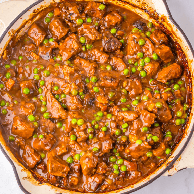Cooked beef pot pie filling spread in a shallow dish to cool before assembly