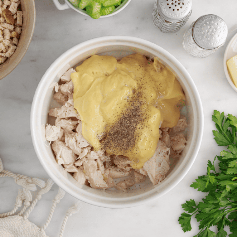 Raw chicken breasts seasoned and placed in a mixing bowl with stuffing mix.