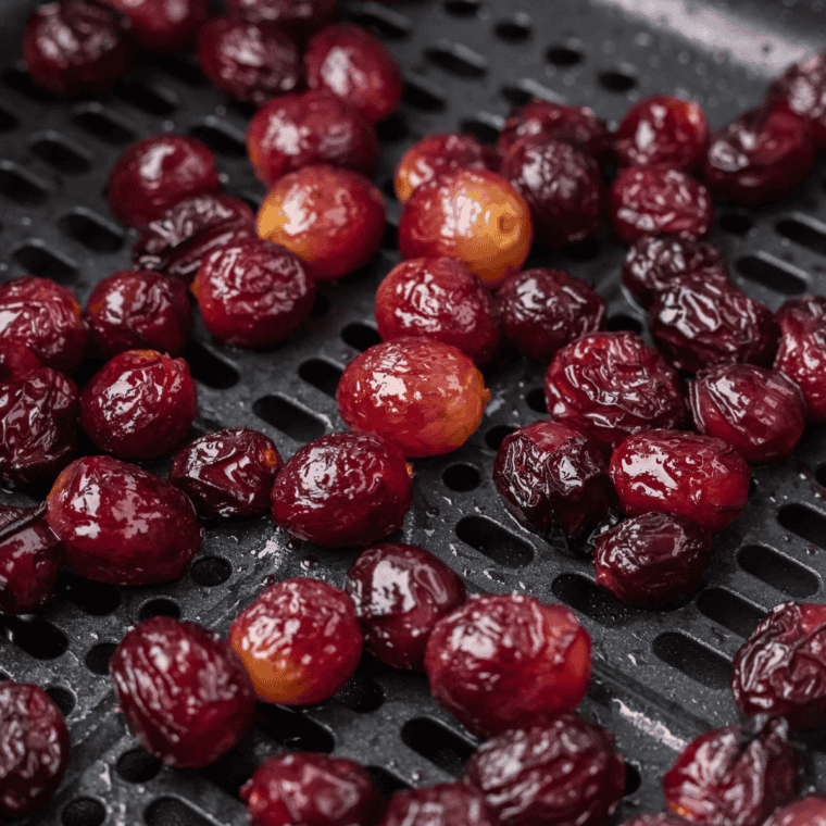 Close-up of caramelized air fryer grapes, golden and chewy, served in a small white bowl. Perfect for a healthy snack or dessert topping.