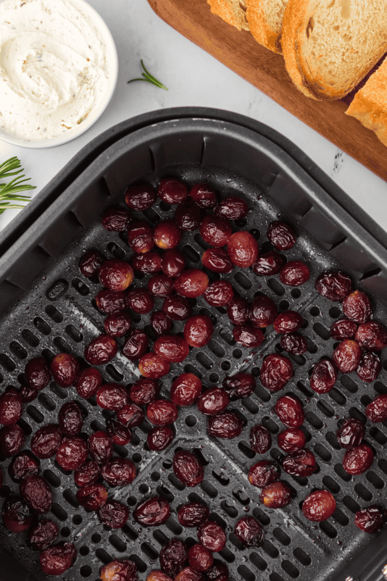 Cooked grapes in an air fryer basket, perfectly roasted and ready to enjoy.