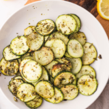 Blackstone griddle zucchini golden and charred with grill marks on white serving plate