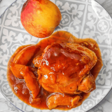 Air fryer peach chicken thighs served on a plate with caramelized peaches and herbs.