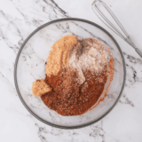 Fiesta seasoning spices measured into a white bowl before mixing