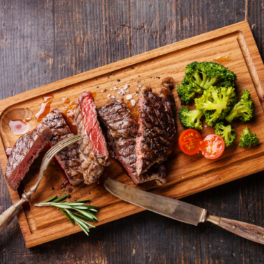 Homemade Heinz 57 steak sauce in a small glass jar beside sliced steak on a wooden cutting board