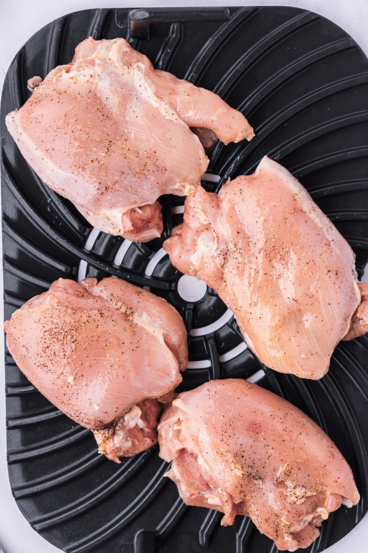 Seasoned chicken thighs cooking on Ninja Foodi grill grate.