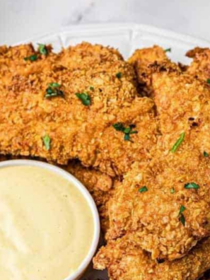 Plate of golden chicken nuggets with a small bowl of homemade Carolina Gold BBQ sauce for dipping
