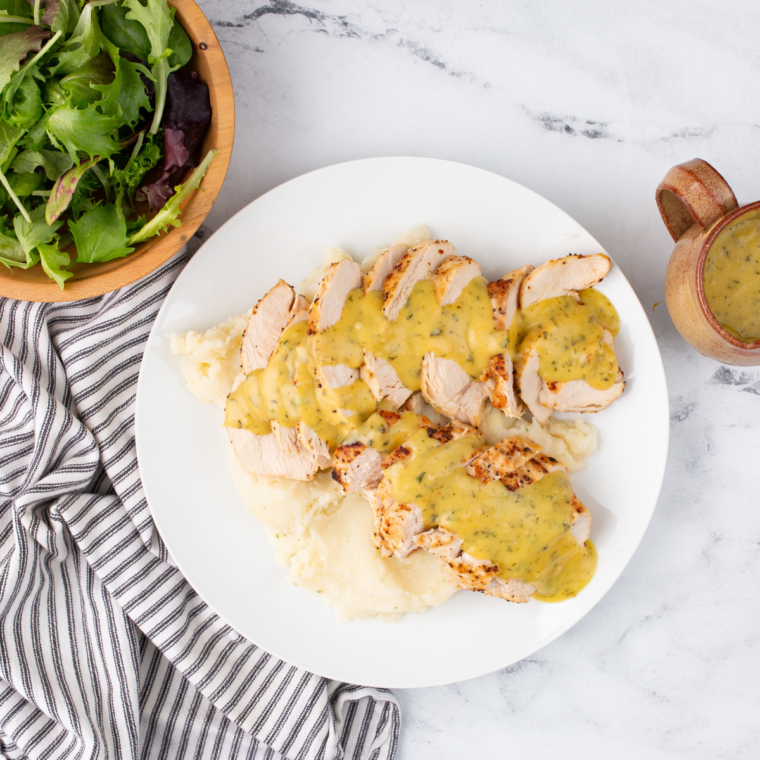 Carolina Gold BBQ sauce drizzled over a sliced chicken breast on a white plate
