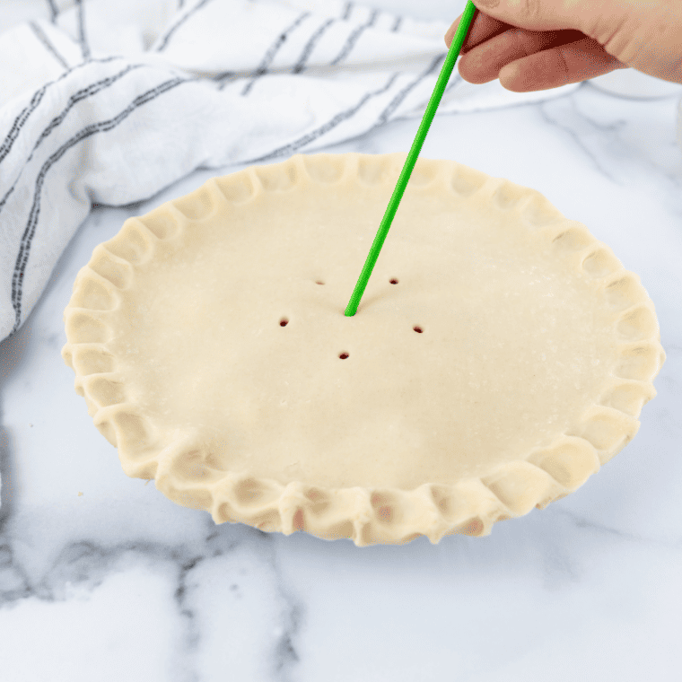 Beating egg yolk with milk in a small bowl and brushing the egg wash over the top crust of the pie for a golden finish.