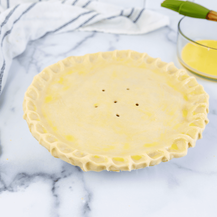 Placing the pie dish into the air fryer basket and air frying the cherry pie at 310°F (175°C) for 10-15 minutes until the crust is golden brown and the filling is bubbly.