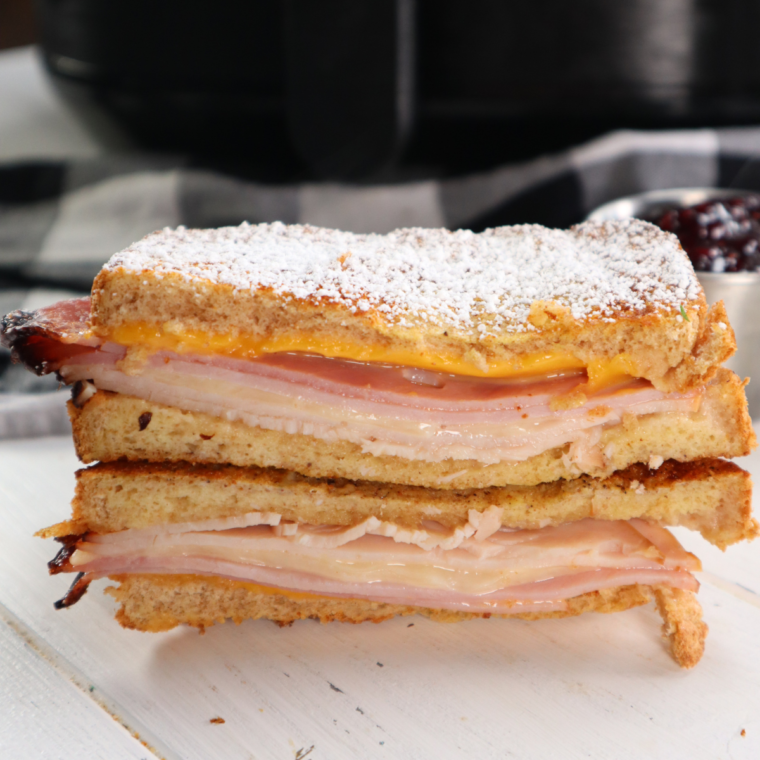 PIcture of 1/2 a monte cristo sandwich sitting on cutting board.