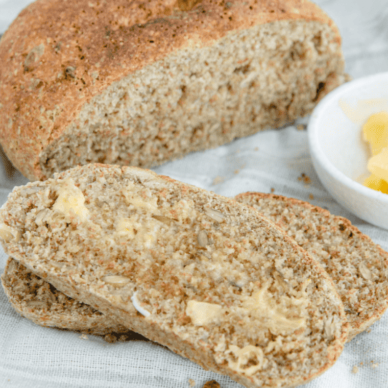 Freshly baked whole wheat bread sliced on a wooden cutting board