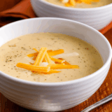 Bowl of creamy Copycat Outback Steakhouse Walkabout Soup topped with shredded cheese and chopped parsley.