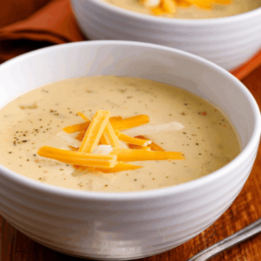 Bowl of creamy Copycat Outback Steakhouse Walkabout Soup topped with shredded cheese and chopped parsley.