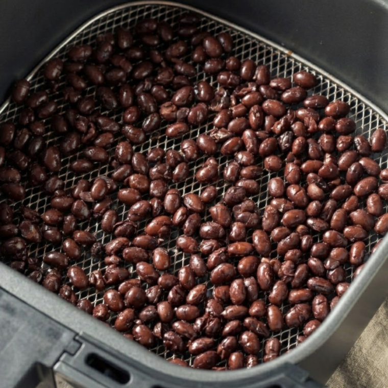 black beans spread in single layer inside air fryer basket