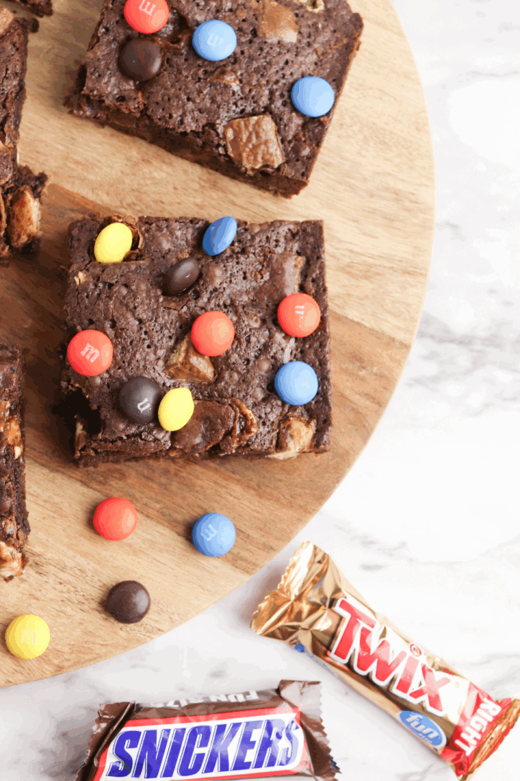 Fudgy brownies packed with chopped leftover Halloween candy, served on a plate