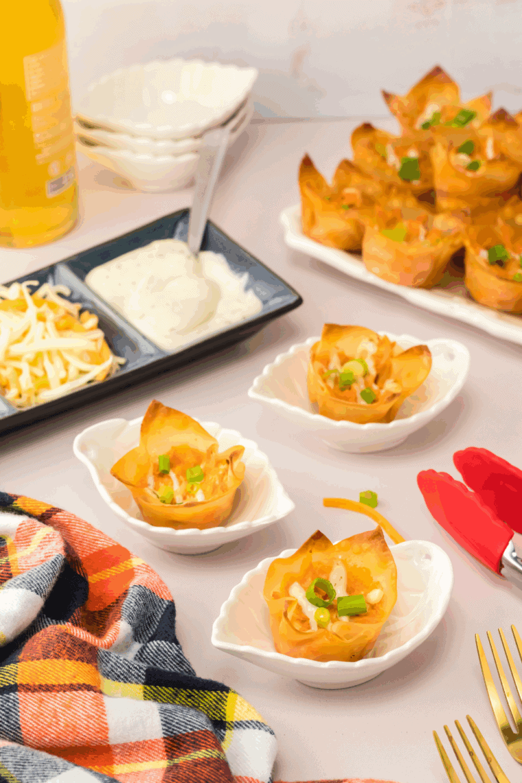 Crispy buffalo chicken rangoons on a white plate, filled with creamy buffalo chicken, served with ranch and buffalo sauce for dipping.