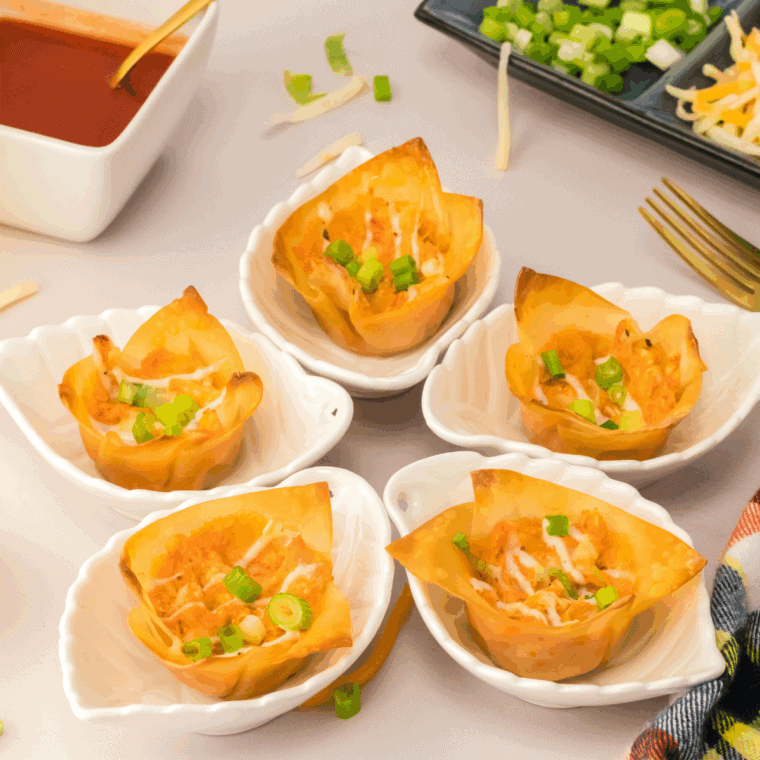 Crispy buffalo chicken rangoons arranged on a serving plate, filled with creamy buffalo chicken and served with a side of ranch dressing for dipping.