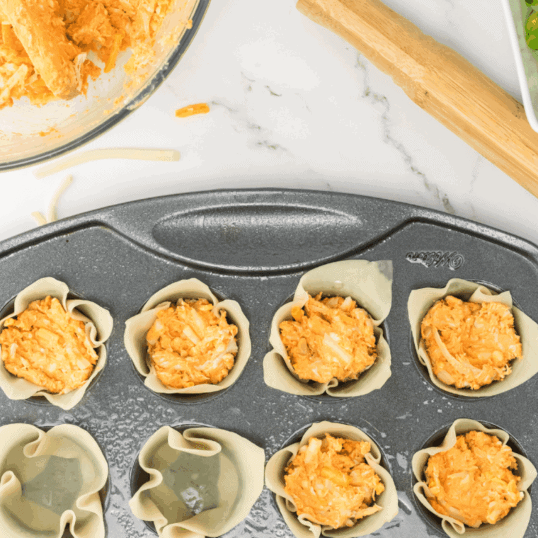Rangoons on a parchment-lined baking tray, baking in the oven at 400°F until golden brown.