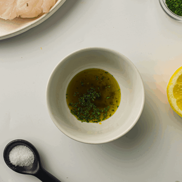Cod fillets seasoned with salt and pepper, topped with pesto, and drizzled with olive oil