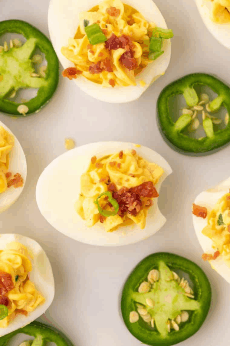 Close-up of creamy Jalapeño Deviled Eggs topped with sliced jalapeños on a serving plate.