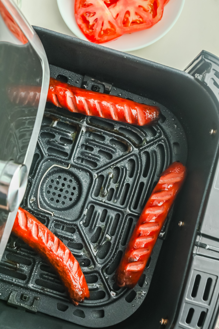 Hot dogs air frying at 350&deg;F while thawing and beginning to firm up.