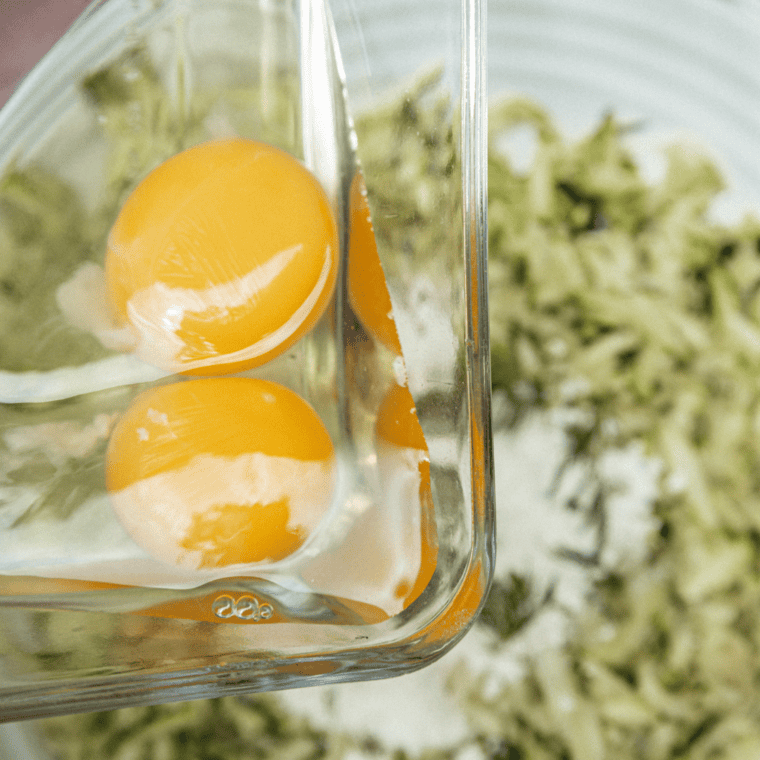 Combine grated zucchini with seasonings and herbs in a bowl.