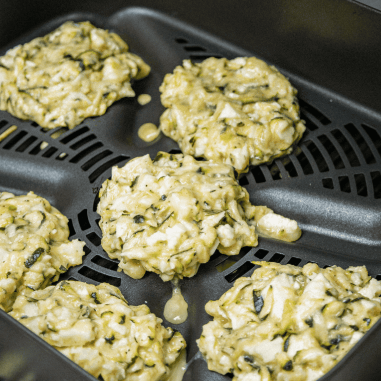 Arrange the zucchini fritters in the air fryer basket, ready to cook.

