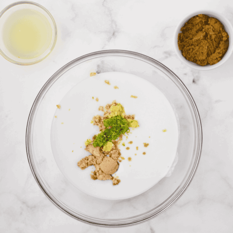 Chicken breasts marinating in a mixture of coconut milk, Thai green curry paste, lime juice, fish sauce, garlic, ginger, and spices in a large bowl.