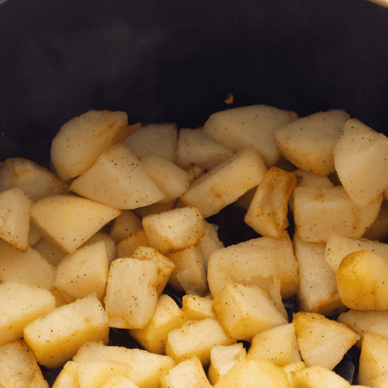 Mashing cooked air-fried apples to make smooth, flavorful applesauce.