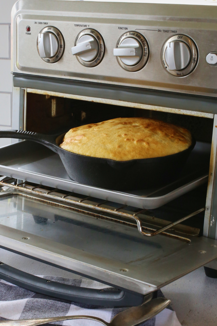 Chili topped with raw cornbread batter going into an air fryer oven on the rack
