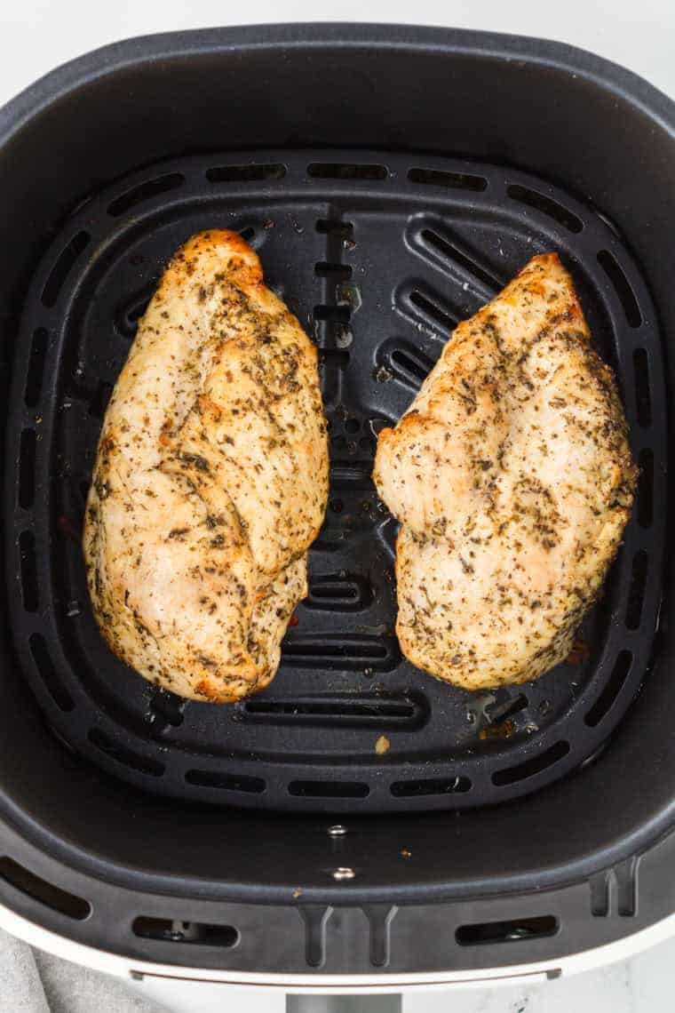 Cooked chicken breasts in the air fryer basket.