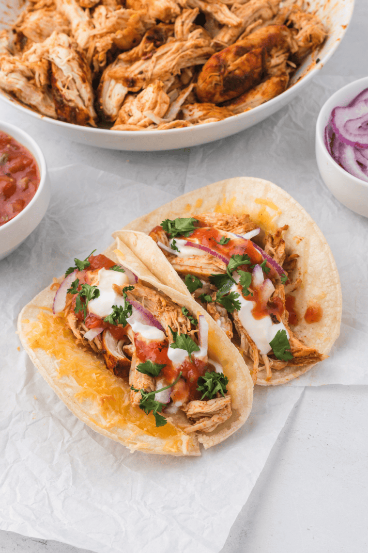 Plate of crockpot shredded chicken tacos topped with cheese, lettuce, and cilantro