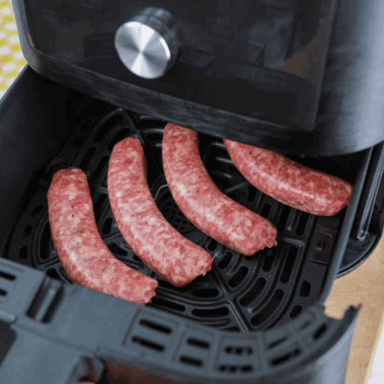 Sliced smoked sausage, red and green bell peppers, and yellow onions tossed in a bowl with olive oil and seasonings.
