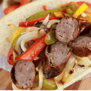 Golden Corral sausage and peppers copycat with browned sausage slices, sautéed red and green peppers, and onions in a skillet.