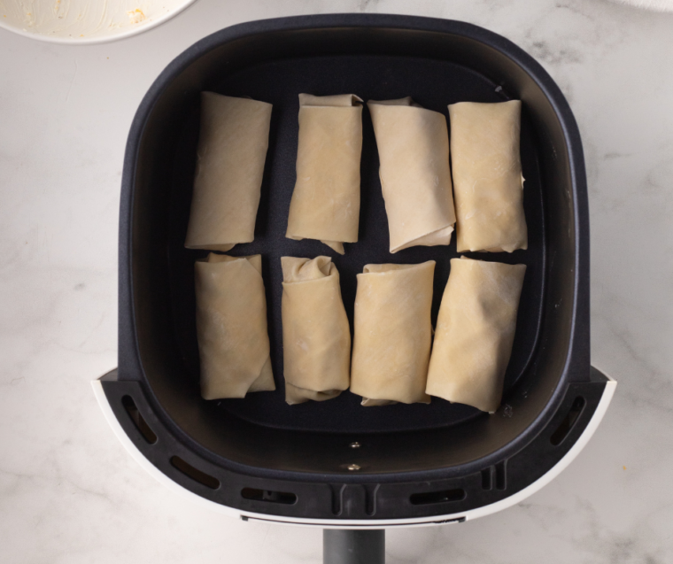 Egg Rolls in the Air Fryer: Egg rolls arranged in the air fryer basket before cooking, ready to be air-fried to a crispy golden brown.