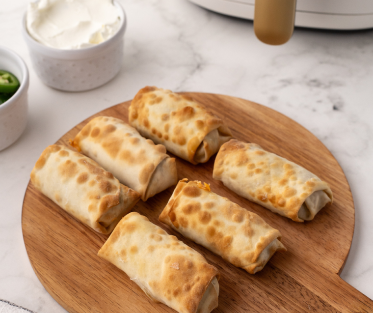 Air Fryer Jalapeno Popper Egg Rolls with Dipping Sauce: A serving of jalapeno popper egg rolls next to a bowl of dipping sauce, highlighting their crispy texture and delicious filling.