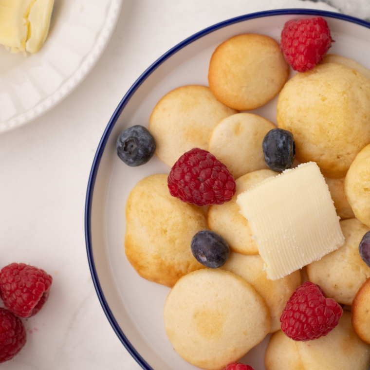 Air fryer mini pancakes served in a bowl with syrup, a fun and quick breakfast idea.