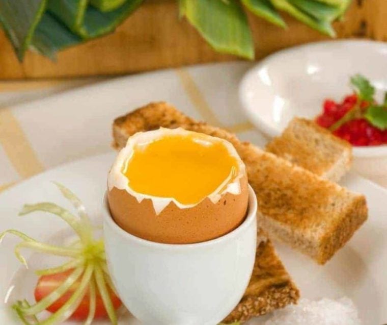 closeup: an air fryer soft boiled egg with the runny yolk showing and toast strips on the side 