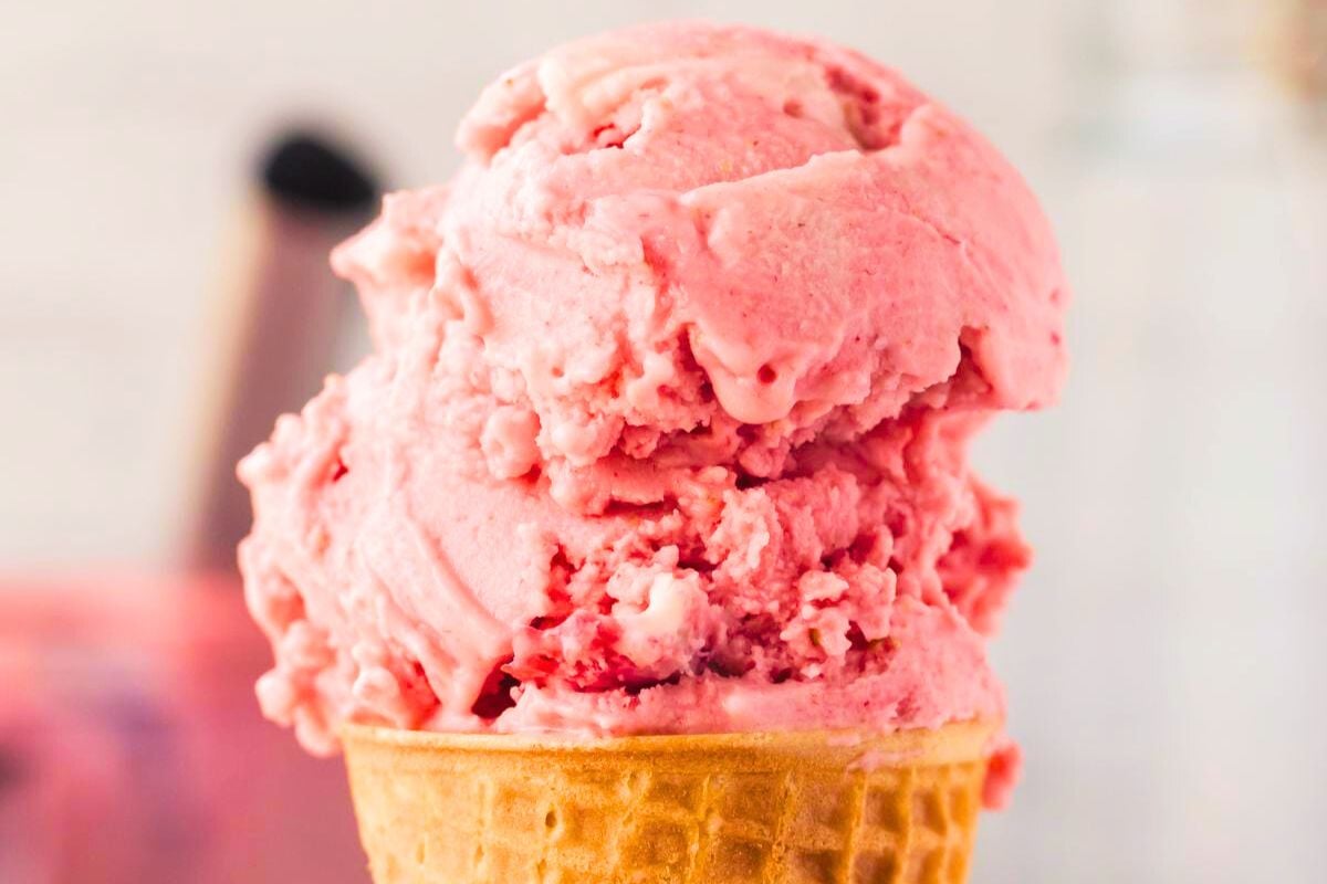 An ice cream cone with strawberry ice cream.