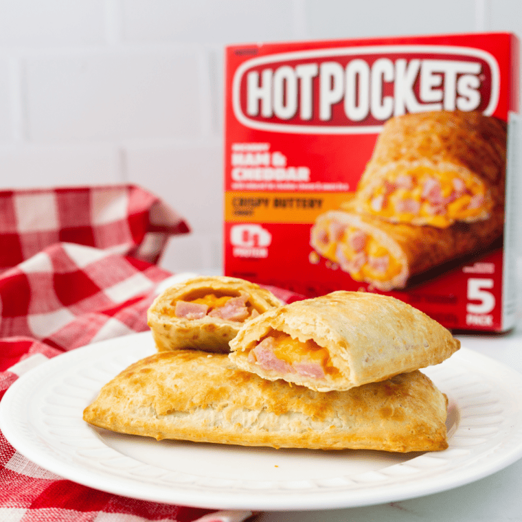 three air fryer hot pockets on a white plate with a box of hot pockets and a white and red checkered cloth