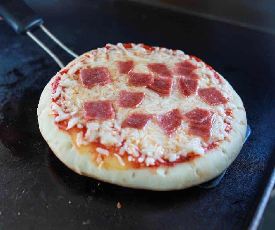 closeup: a spatula lifting a blackstone pizza from the griddle