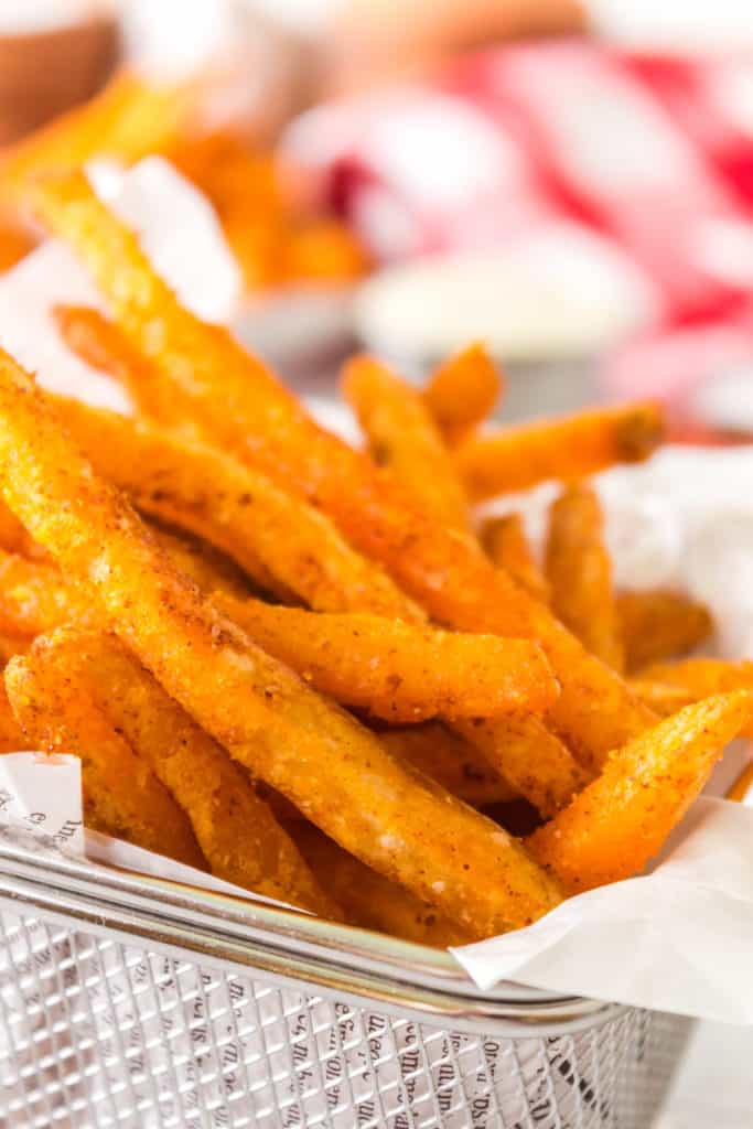 closeup: checkers fries air fryer recipe in a metal fry basket with parchment paper