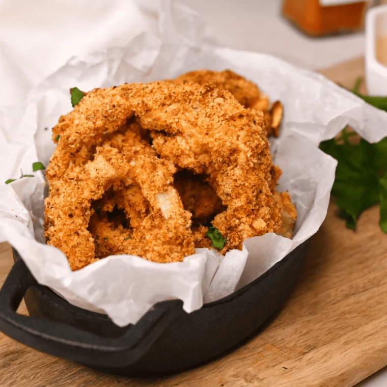 closeup: my frozen onion rings air fryer recipe in a small cast iron dish with parchment